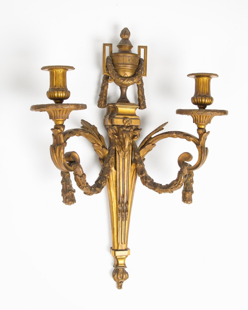 A pair of 19th-century French Neoclassical gilt bronze two-arm wall sconces featuring urn finials, rams head masks, fluted central shafts, and drapery swags. View III
