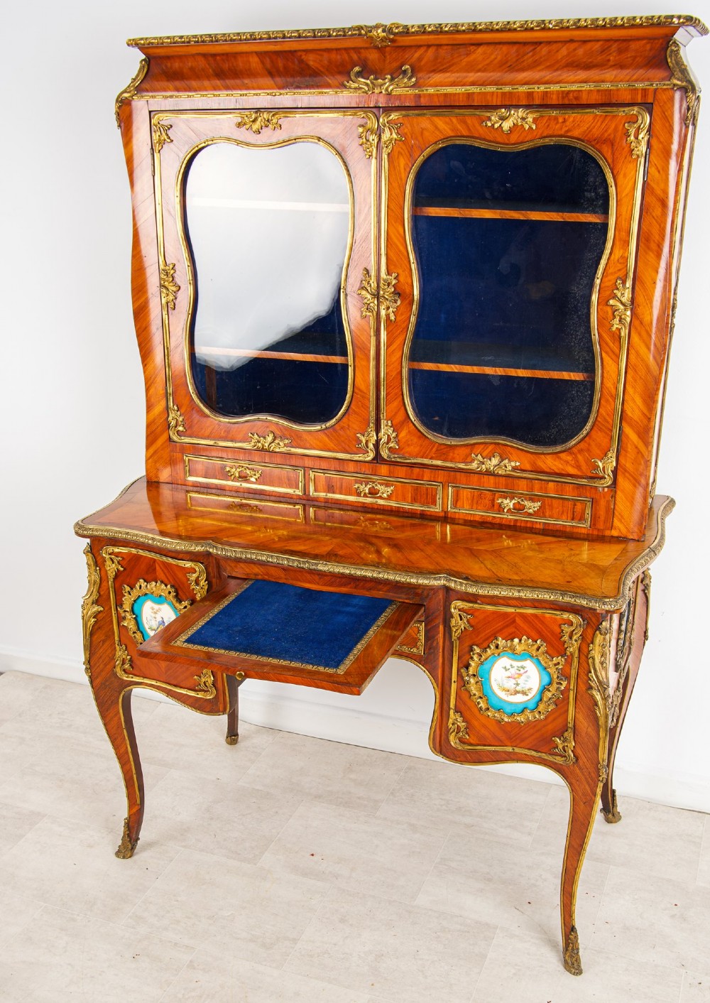 An antique French kingwood Bonheur du Jour cabinet featuring glazed upper doors, ornate ormolu mounts, Sevres style porcelain plaques, and cabriole legs. View III