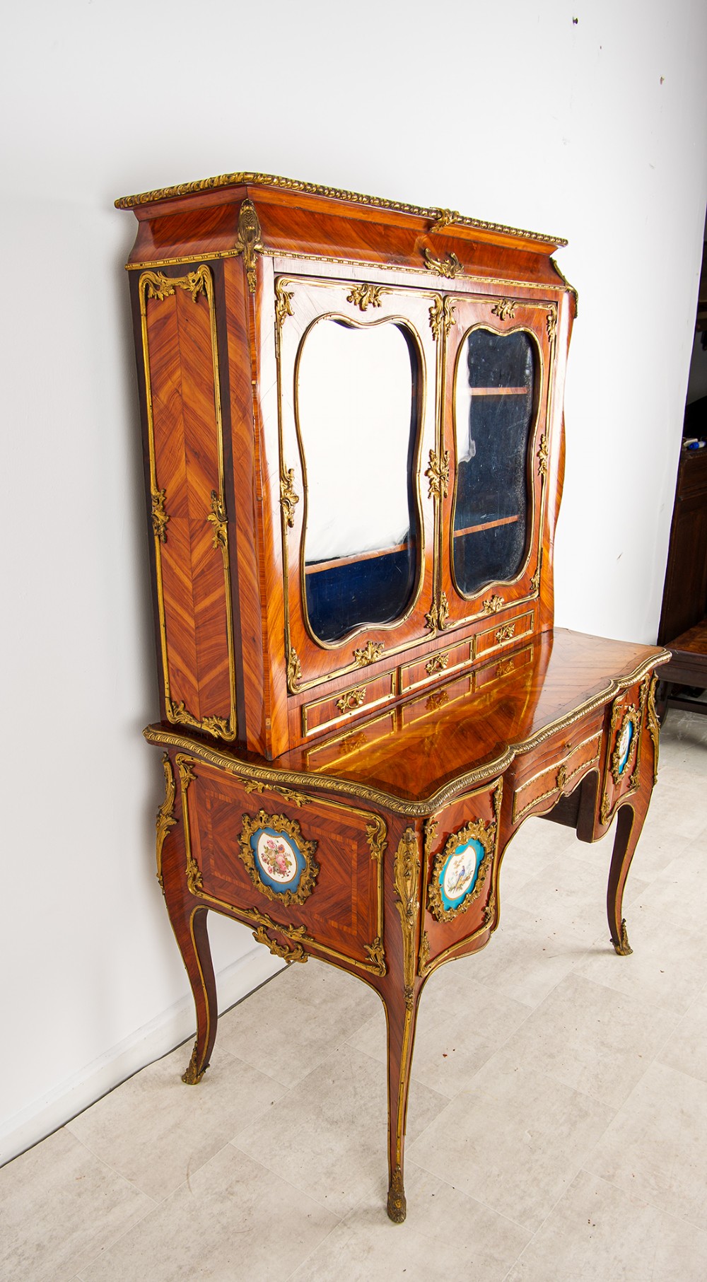 An antique French kingwood Bonheur du Jour cabinet featuring glazed upper doors, ornate ormolu mounts, Sevres style porcelain plaques, and cabriole legs. View IV