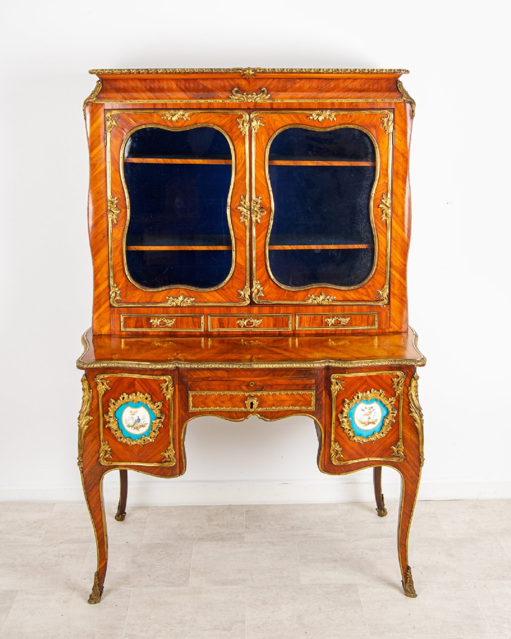 An antique French kingwood Bonheur du Jour cabinet featuring glazed upper doors, ornate ormolu mounts, Sevres style porcelain plaques, and cabriole legs. View V