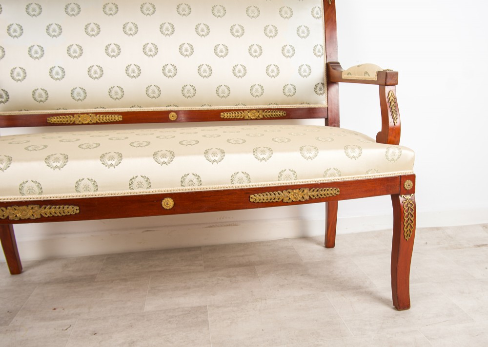 A French Empire Revival mahogany settee with cream patterned silk upholstery, curved arms, and gilded metal ormolu mounts. View IV