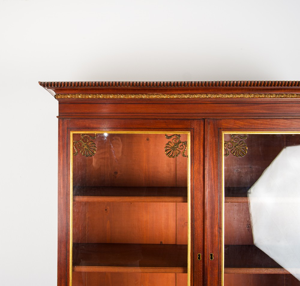 An antique Regency mahogany glazed bookcase cabinet with brass decorative mounts, fluted columns, and a lower two-door cupboard. View IV
