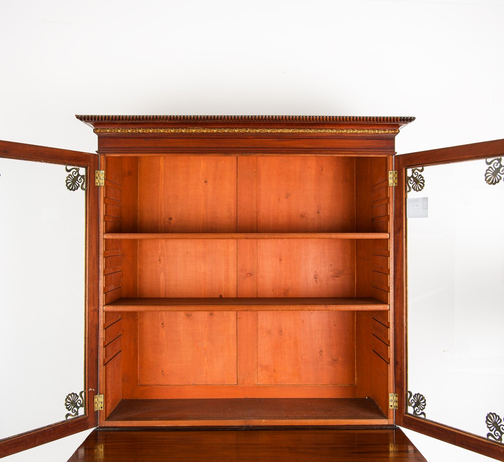 An antique Regency mahogany glazed bookcase cabinet with brass decorative mounts, fluted columns, and a lower two-door cupboard. View V