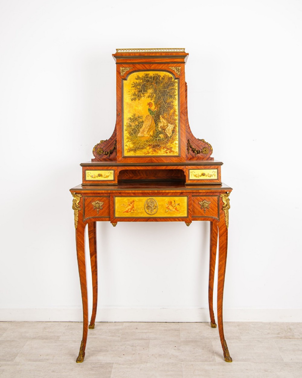 A nineteenth-century French kingwood writing cabinet featuring slender cabriole legs, gilt-bronze mounts, and a central Vernis Martin painted panel depicting a pastoral scene.