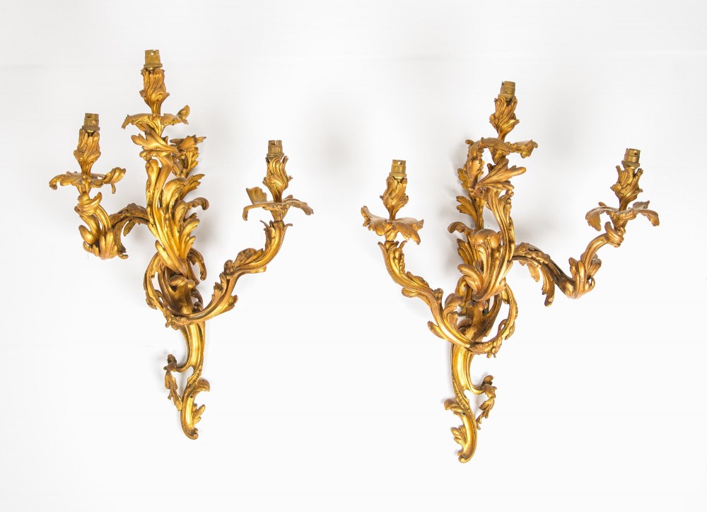 A pair of gilt bronze French ormolu three-branch wall lights decorated with sweeping Rococo acanthus leaf scrollwork. View II