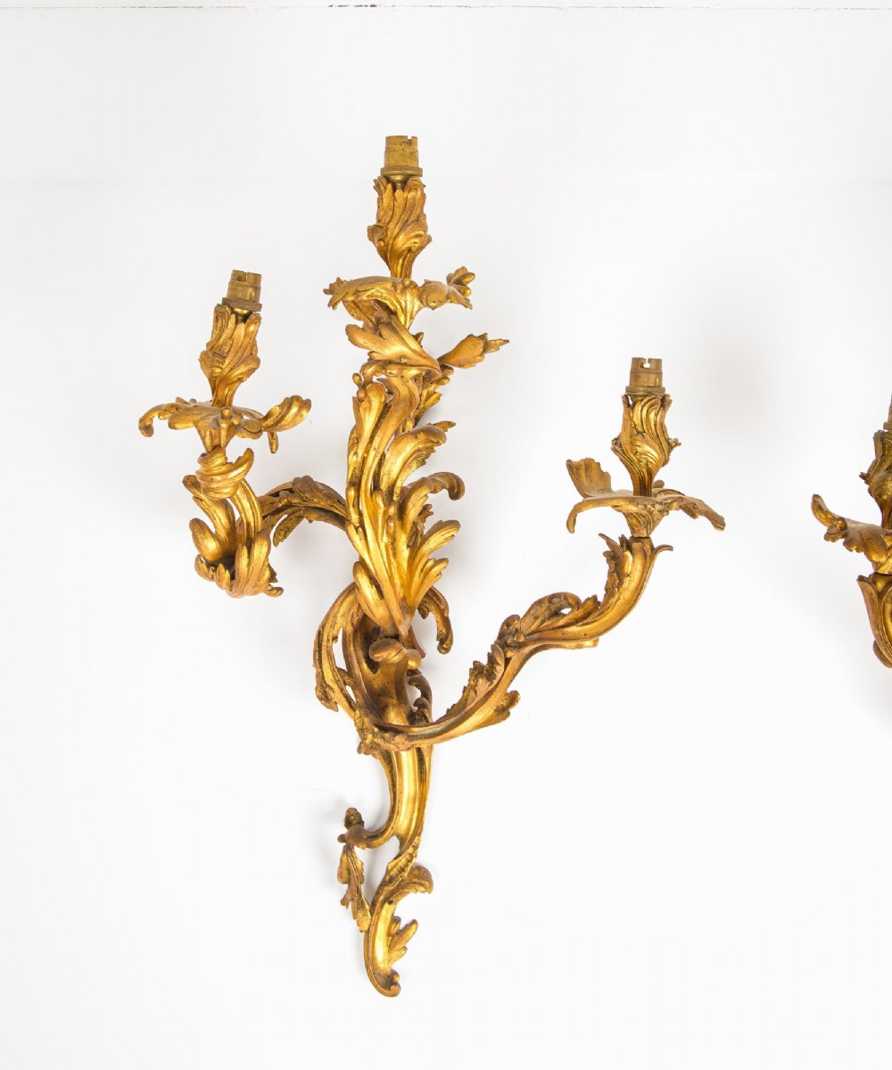 A pair of gilt bronze French ormolu three-branch wall lights decorated with sweeping Rococo acanthus leaf scrollwork. View III