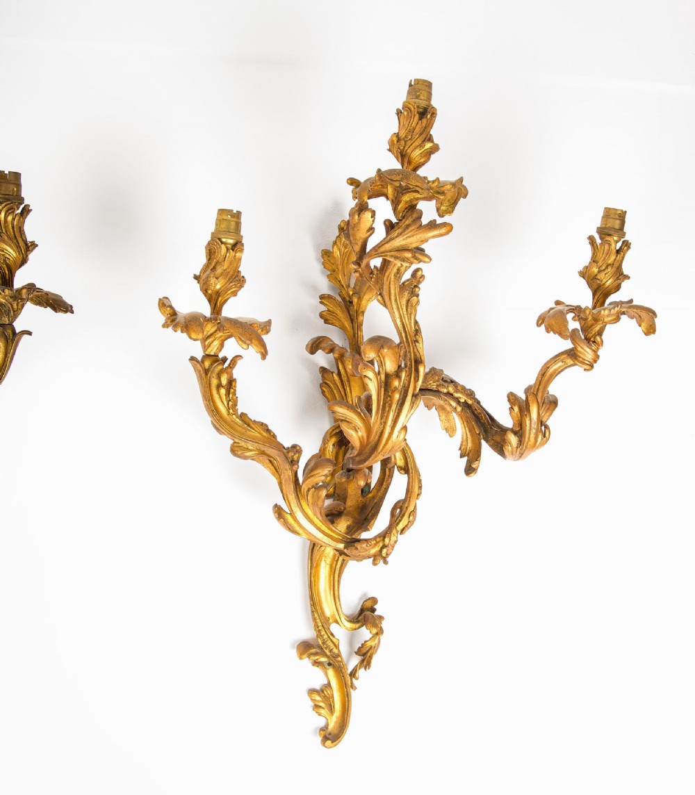 A pair of gilt bronze French ormolu three-branch wall lights decorated with sweeping Rococo acanthus leaf scrollwork. View IV
