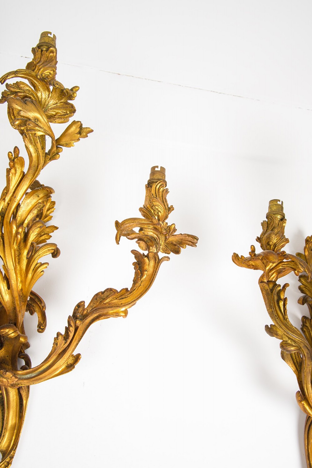 A pair of gilt bronze French ormolu three-branch wall lights decorated with sweeping Rococo acanthus leaf scrollwork. View V