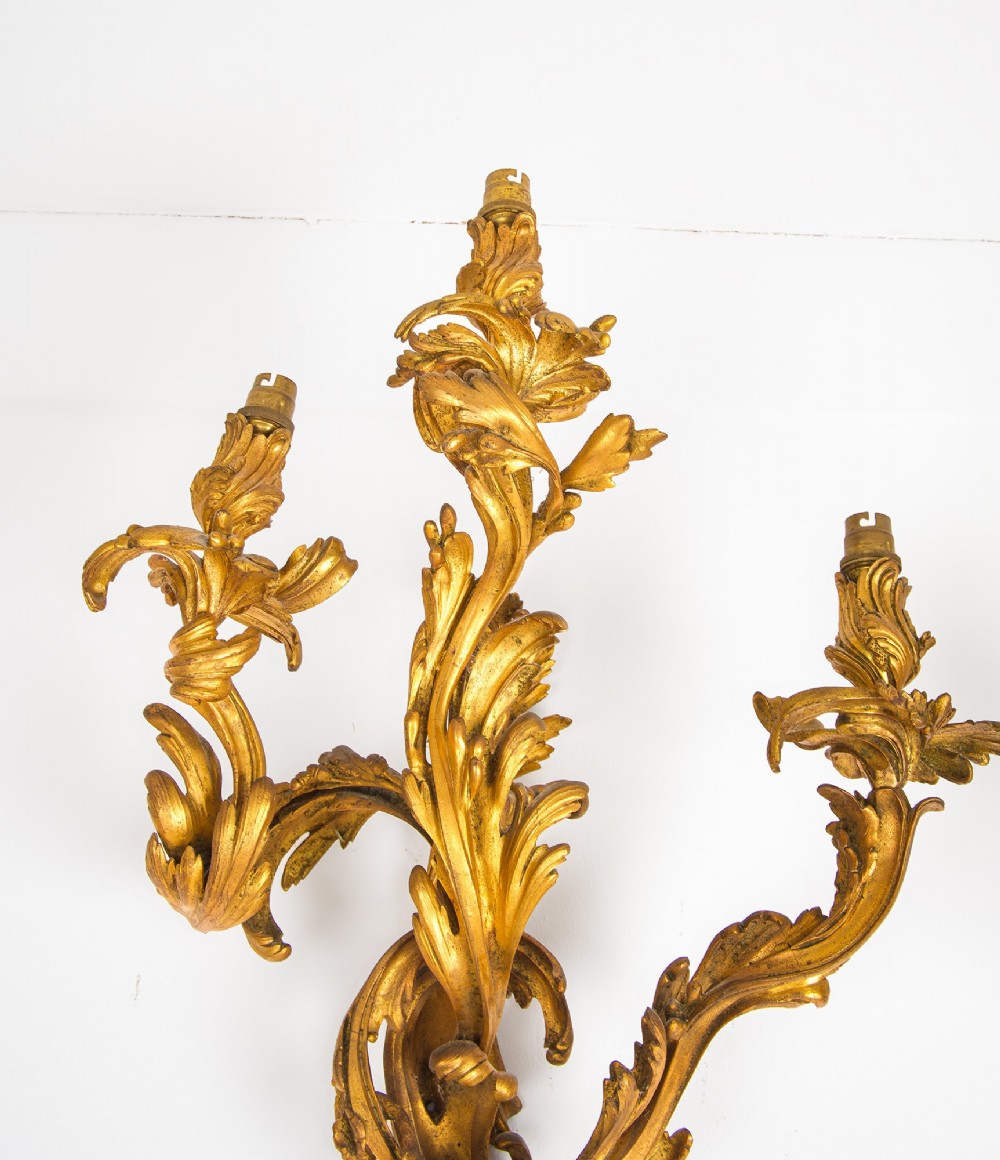 A pair of gilt bronze French ormolu three-branch wall lights decorated with sweeping Rococo acanthus leaf scrollwork. View VI