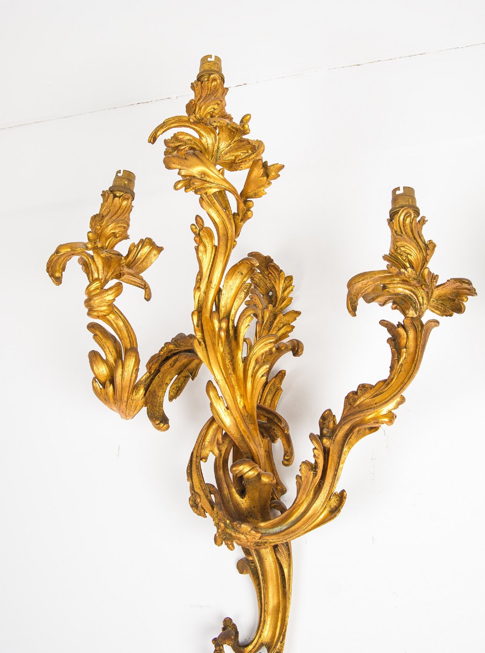 A pair of gilt bronze French ormolu three-branch wall lights decorated with sweeping Rococo acanthus leaf scrollwork. View IX