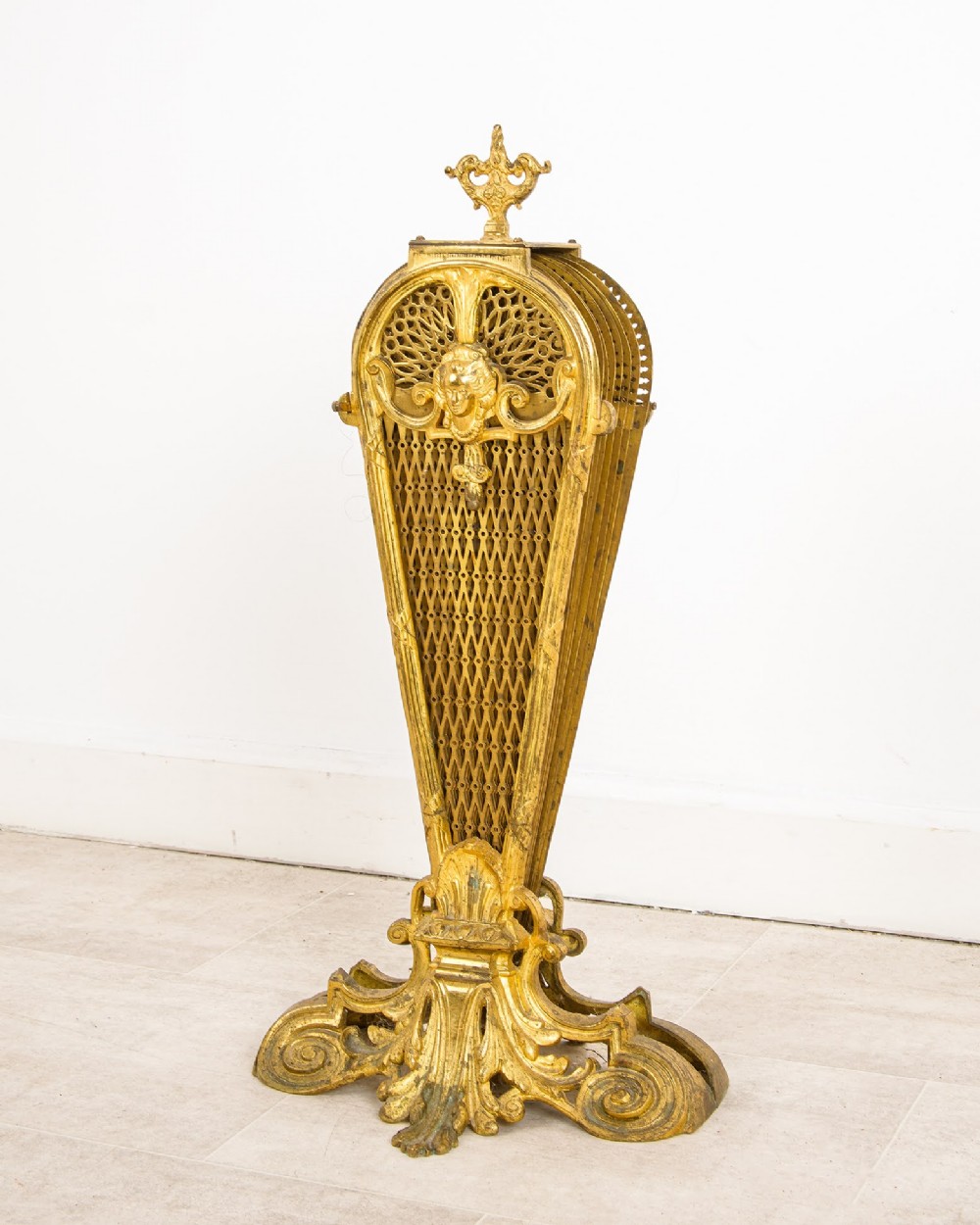 A French gilt brass peacock fan fire screen featuring pierced filigree blades unfolding from a central Rococo scroll base. View III