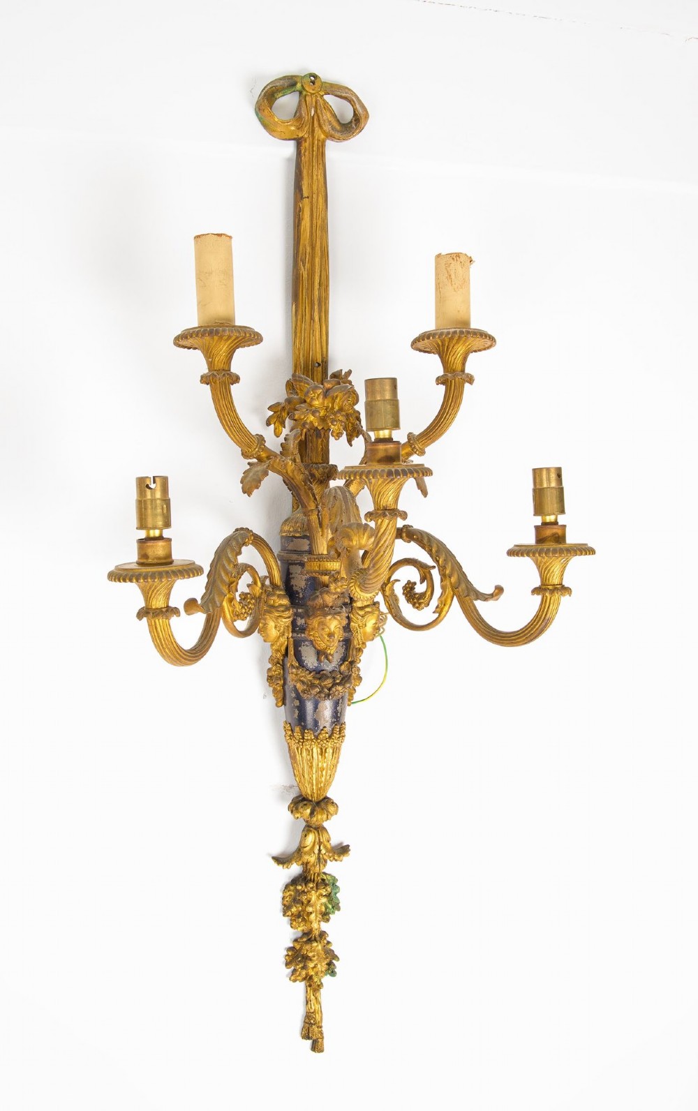 A pair of French Louis XVI style gilt-bronze five-light wall sconces featuring ribbon bow tops, leaf motifs, and classical mask details. View V