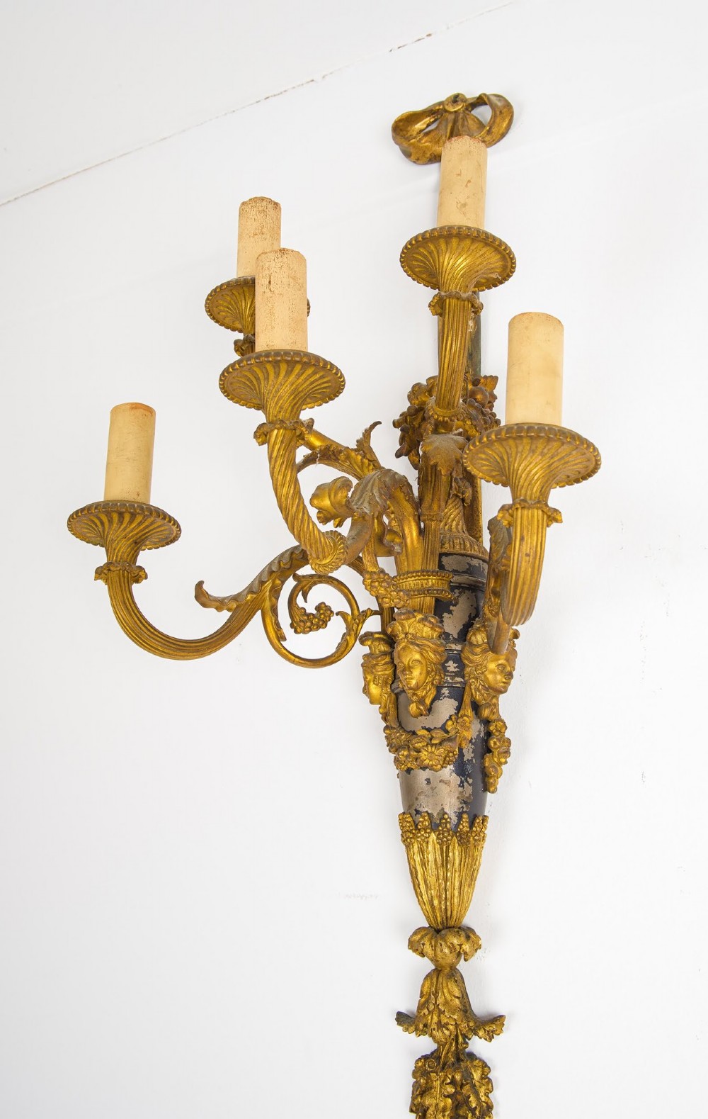 A pair of French Louis XVI style gilt-bronze five-light wall sconces featuring ribbon bow tops, leaf motifs, and classical mask details. View VI