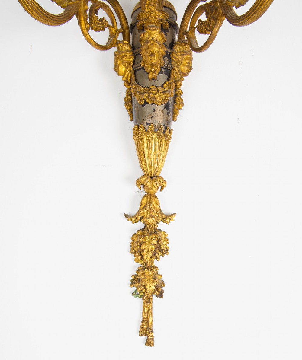A pair of French Louis XVI style gilt-bronze five-light wall sconces featuring ribbon bow tops, leaf motifs, and classical mask details. View VIII