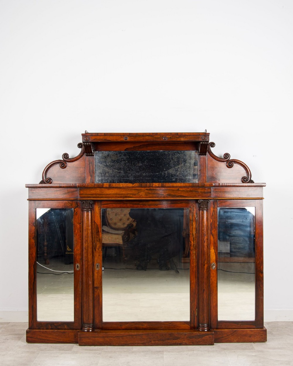 A Victorian rosewood side cabinet featuring a scroll-carved upper back with a shelf and mirror, positioned above three glass-panelled cupboard doors. View II