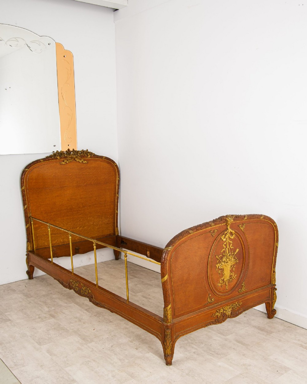 An antique French Louis XV style daybed featuring polished walnut panels, giltwood rococo carvings, and brass side rails.