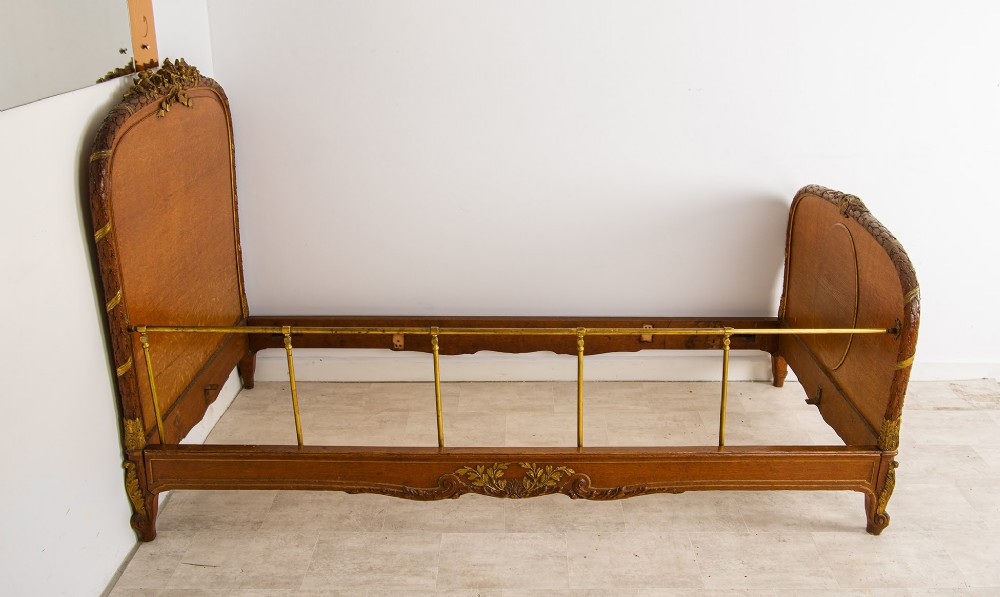 An antique French Louis XV style daybed featuring polished walnut panels, giltwood rococo carvings, and brass side rails. View III