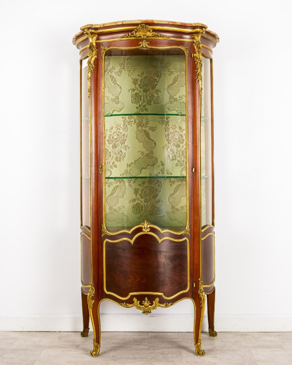 An antique French Louis XV style vitrine cabinet featuring a marble top, glass panels, a fabric-lined interior with glass shelves, and gilt bronze mounts throughout. View II