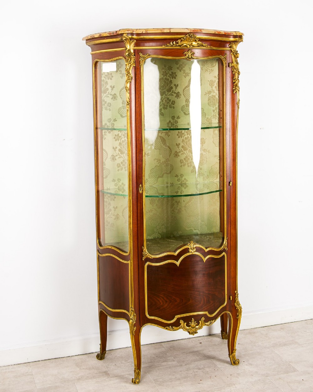 An antique French Louis XV style vitrine cabinet featuring a marble top, glass panels, a fabric-lined interior with glass shelves, and gilt bronze mounts throughout. View IV