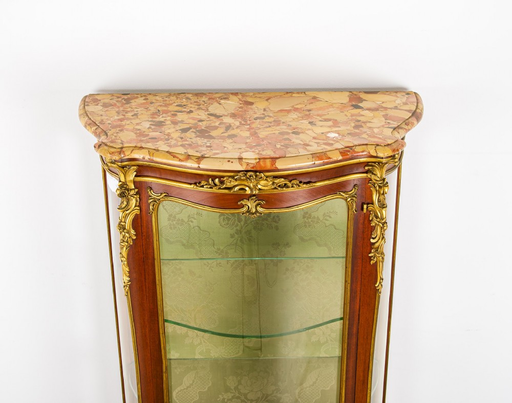 An antique French Louis XV style vitrine cabinet featuring a marble top, glass panels, a fabric-lined interior with glass shelves, and gilt bronze mounts throughout. View VII