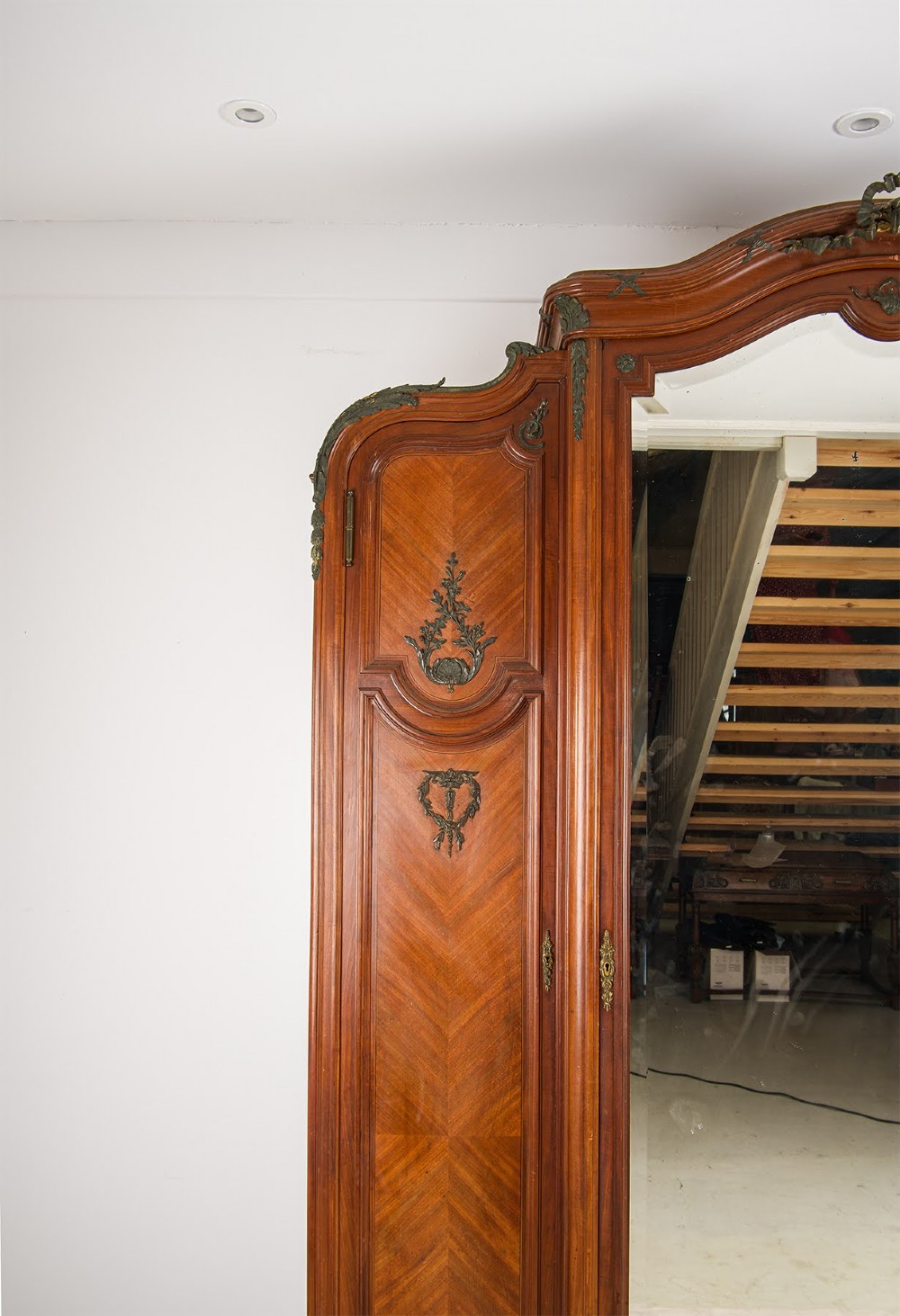 An antique French mahogany three-door armoire featuring a central arched mirrored door flanked by parquetry wood panels with gilt bronze ormolu mounts. View III