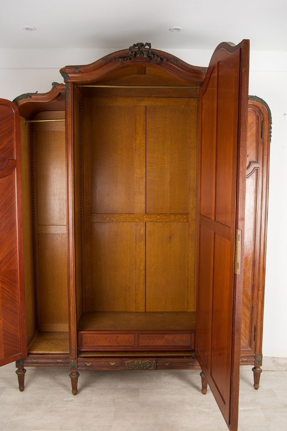 An antique French mahogany three-door armoire featuring a central arched mirrored door flanked by parquetry wood panels with gilt bronze ormolu mounts. View IV