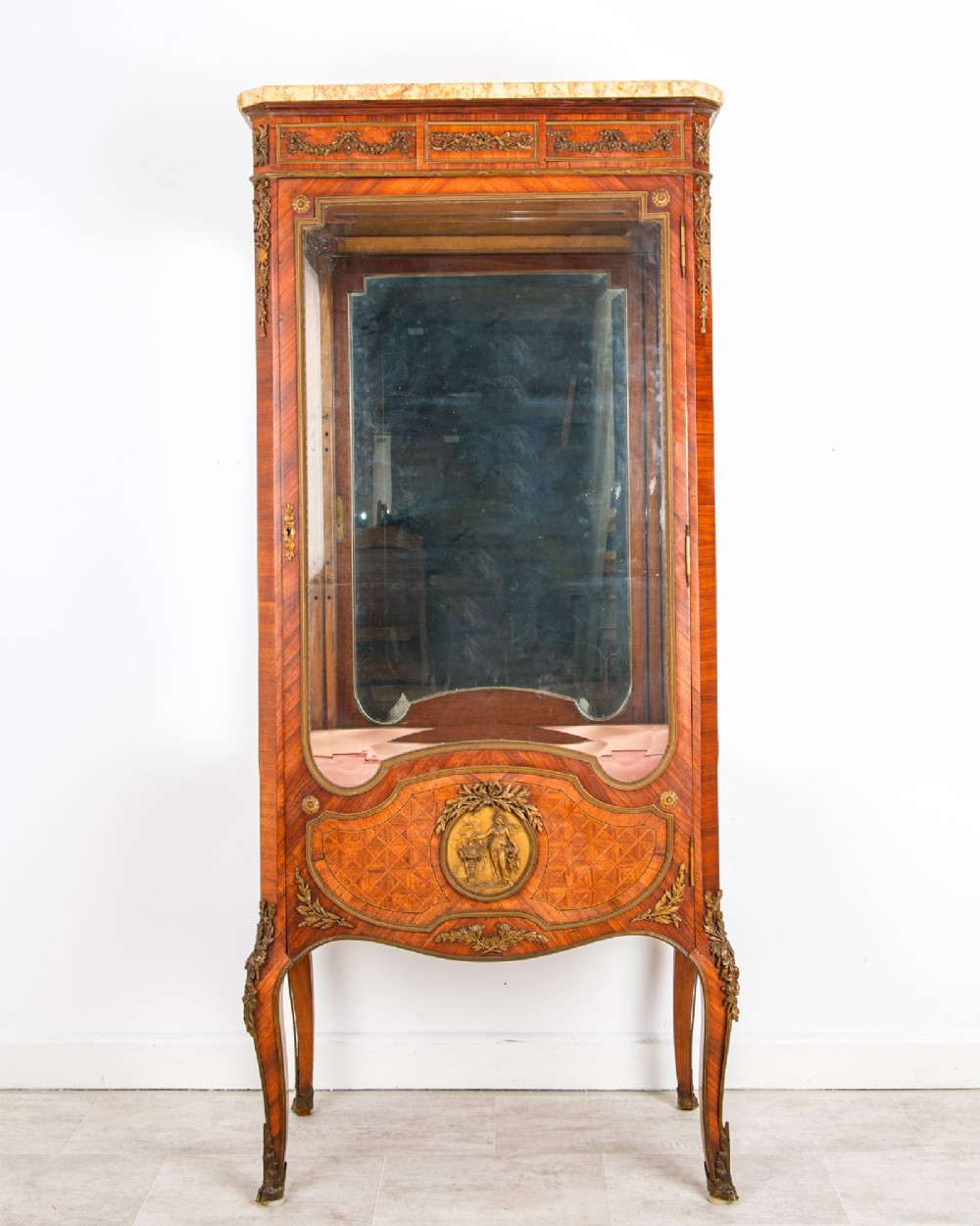 An antique French kingwood vitrine cabinet featuring ornate ormolu mounts, a glazed door with a mirrored interior back, and a contoured marble top resting on slender cabriole legs.
