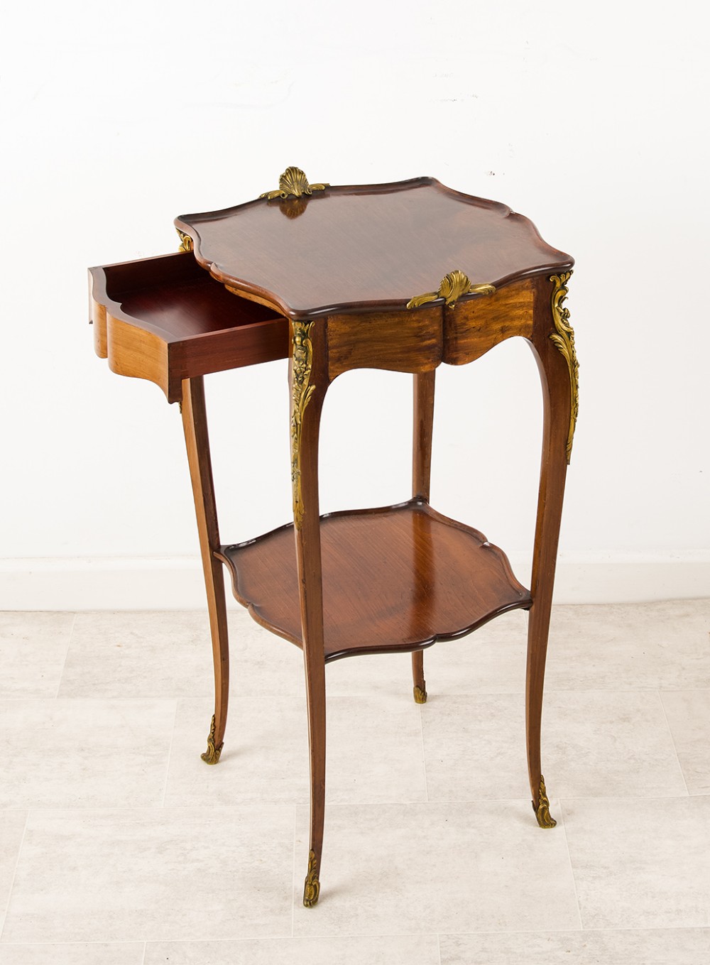 A French Louis XV style mahogany side table featuring gilt bronze mounts, cabriole legs, a serpentine upper top, and a lower tier shelf. View II
