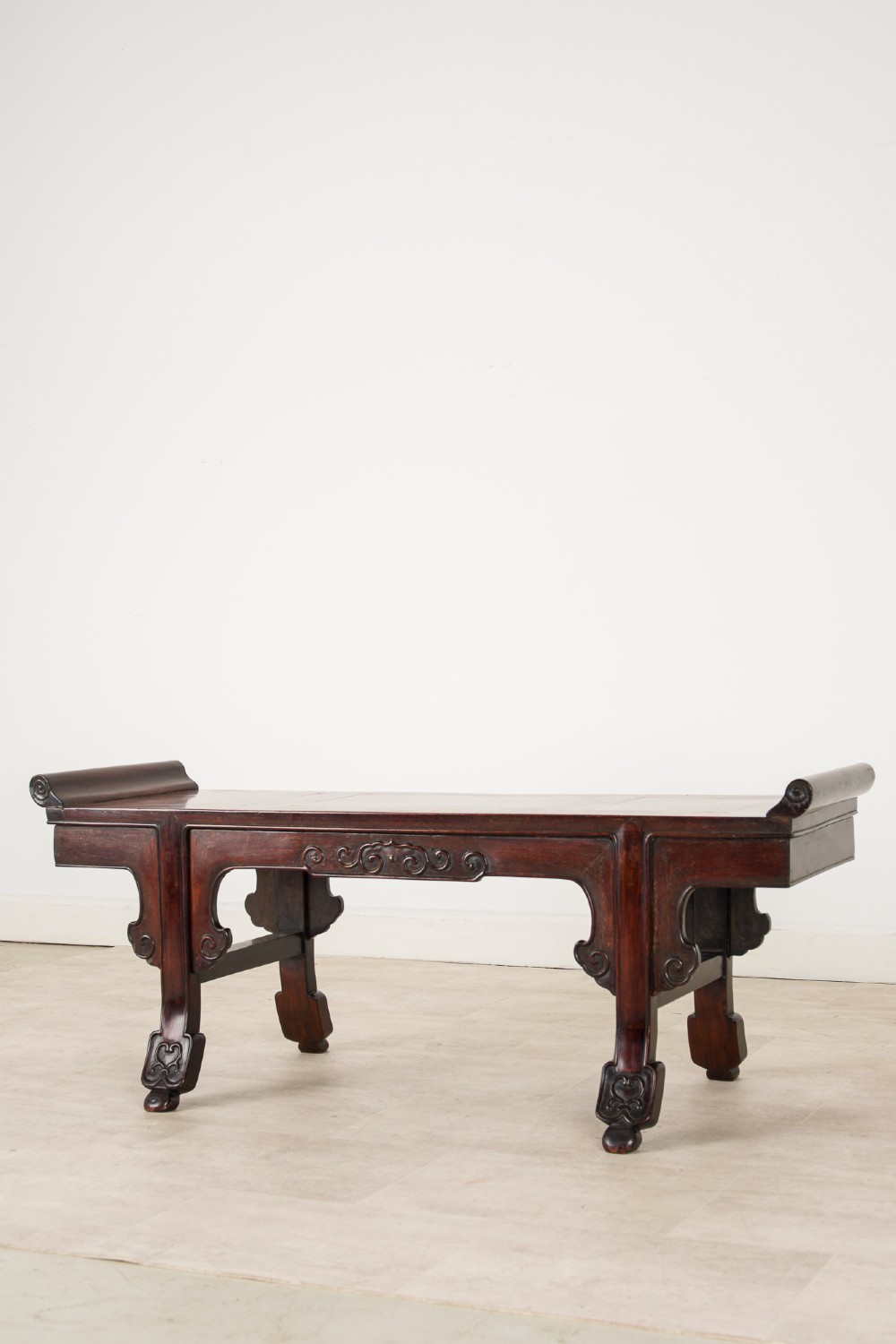 A nineteenth-century Chinese dark hardwood altar bench featuring raised scroll ends, a carved apron, and spandrels. View III