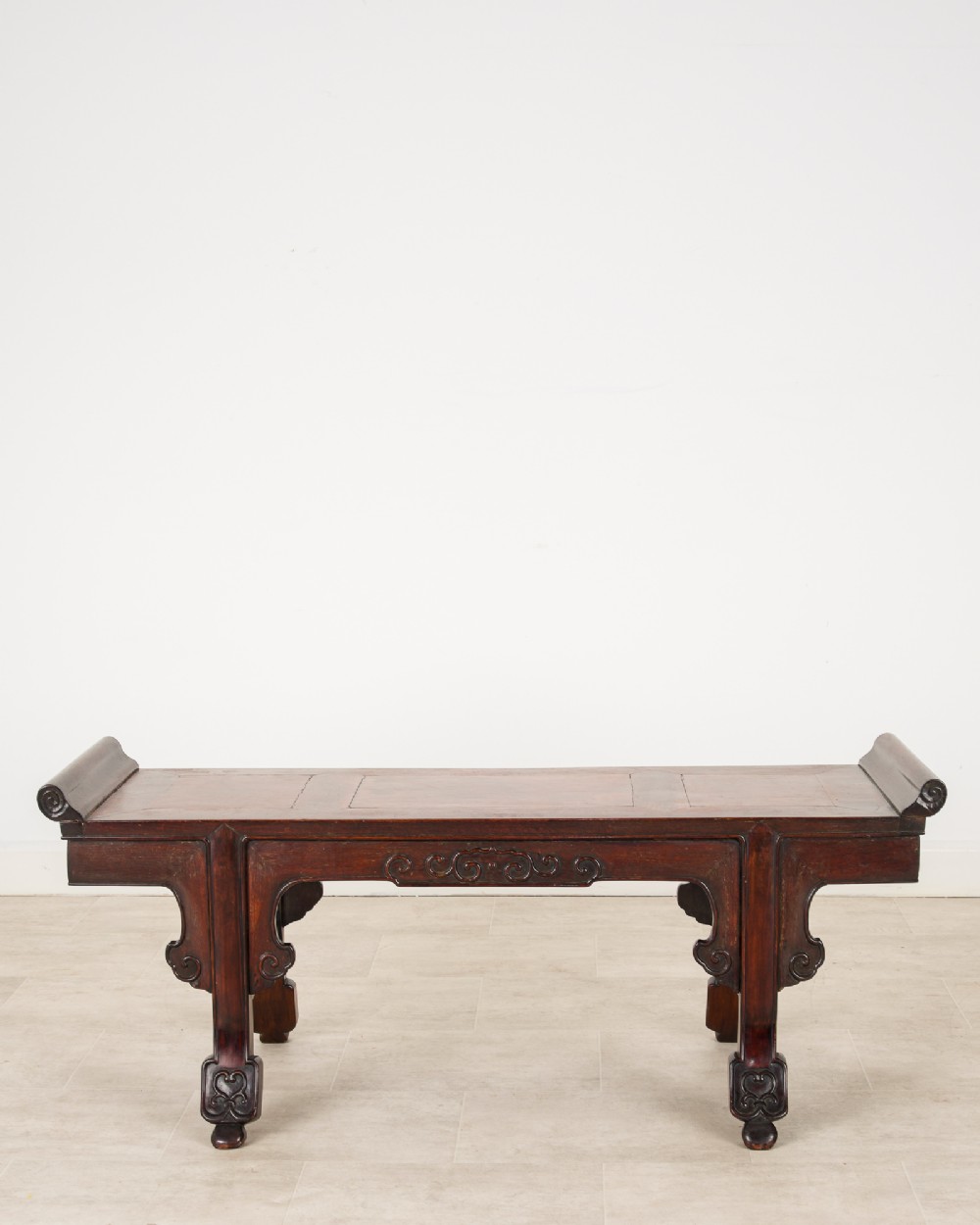 A nineteenth-century Chinese dark hardwood altar bench featuring raised scroll ends, a carved apron, and spandrels. View VI