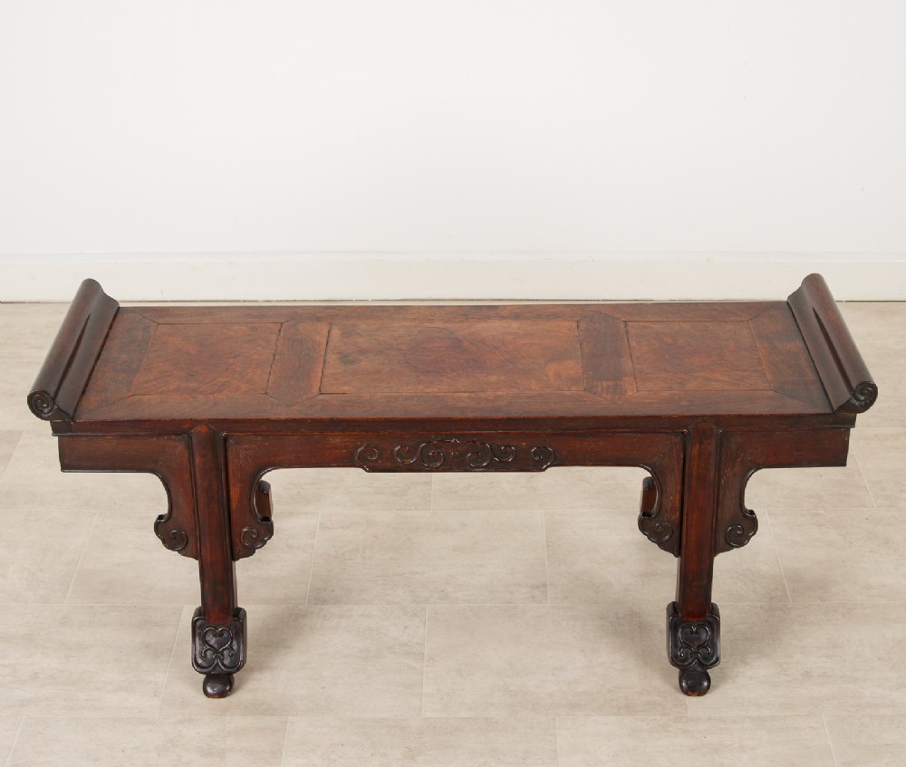 A nineteenth-century Chinese dark hardwood altar bench featuring raised scroll ends, a carved apron, and spandrels. View VII