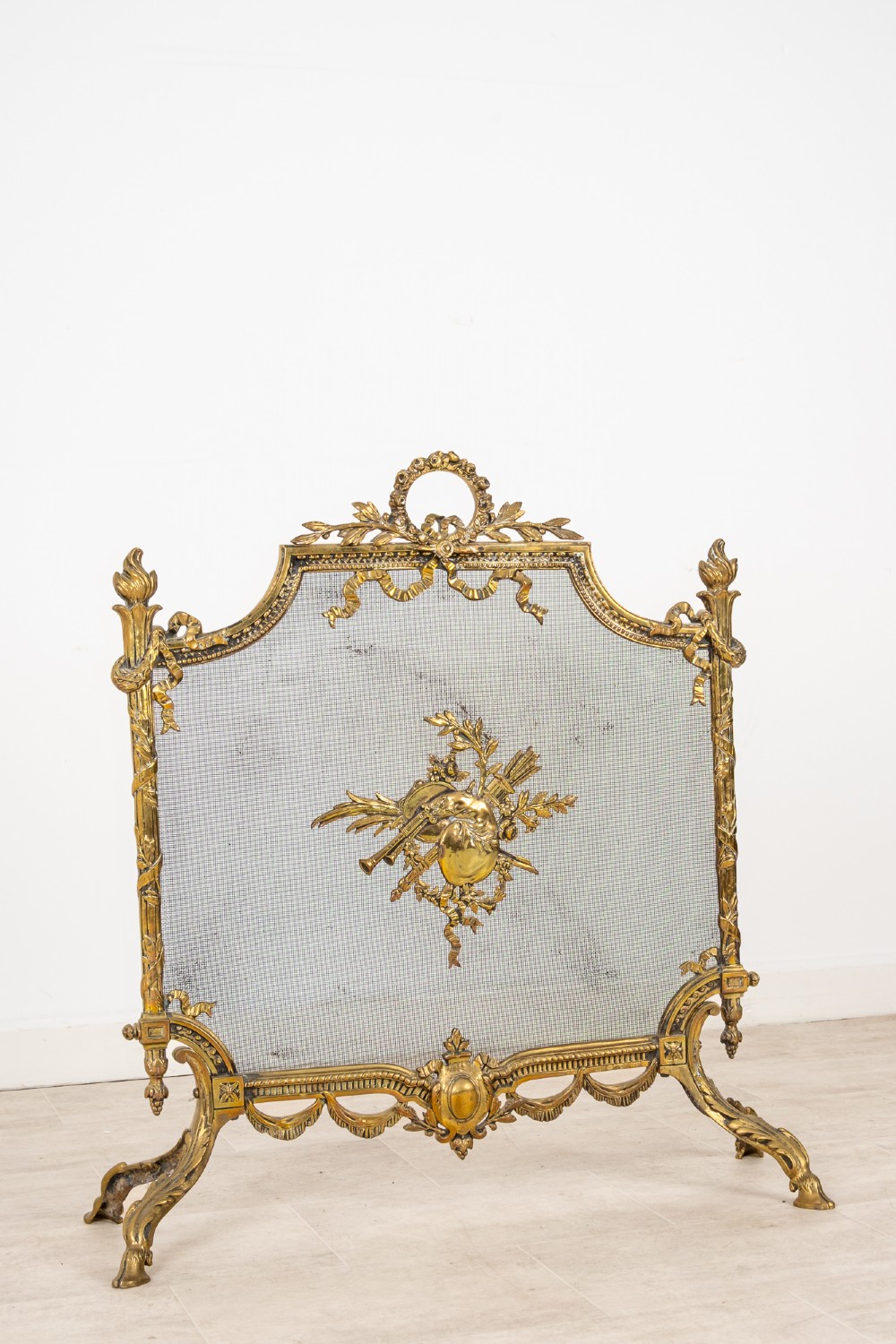 An antique French Louis XVI style gilt brass fire screen featuring a woven mesh panel decorated with a central trophy motif, ribbon bow cresting, and scrolled feet. View III