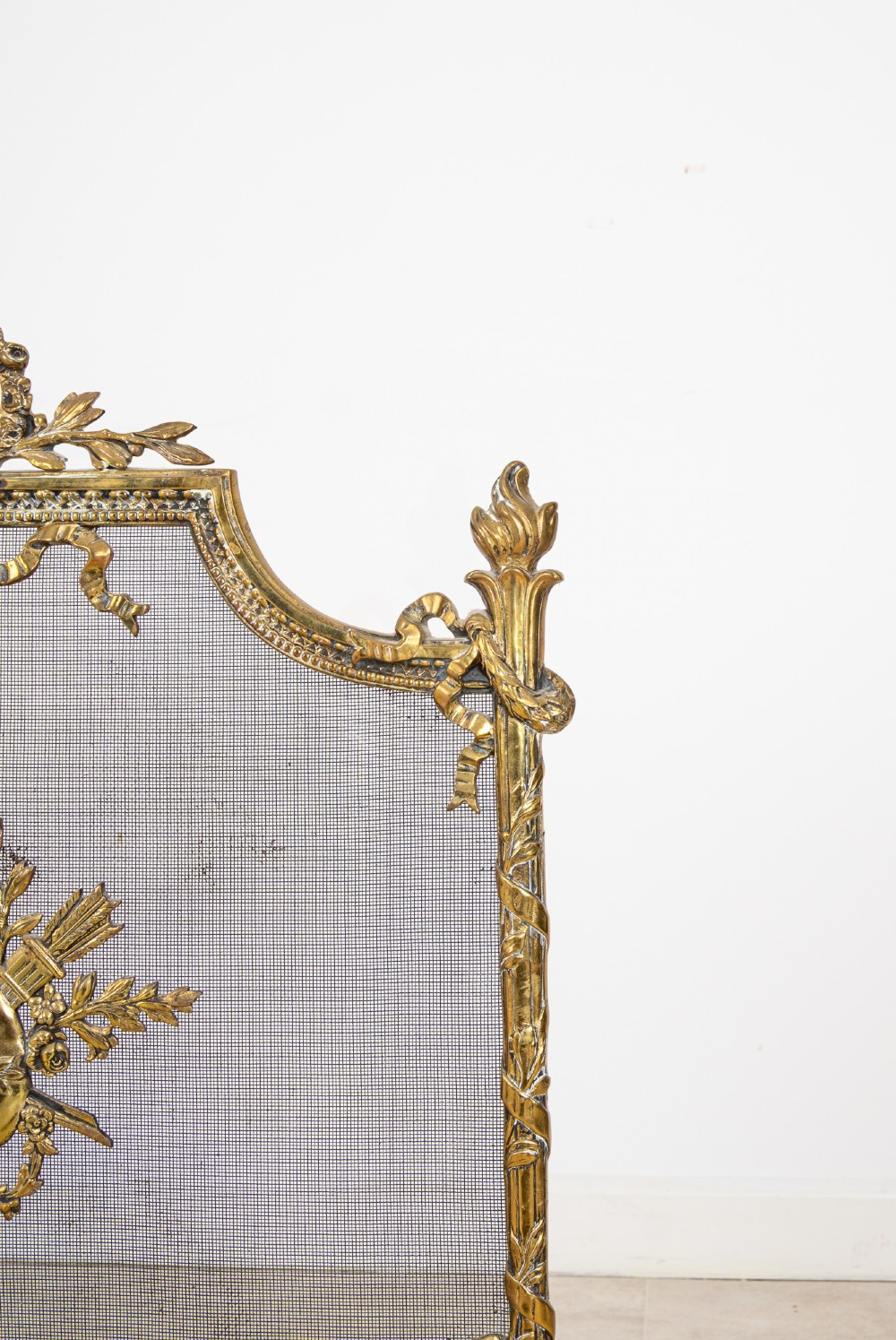 An antique French Louis XVI style gilt brass fire screen featuring a woven mesh panel decorated with a central trophy motif, ribbon bow cresting, and scrolled feet. View VII