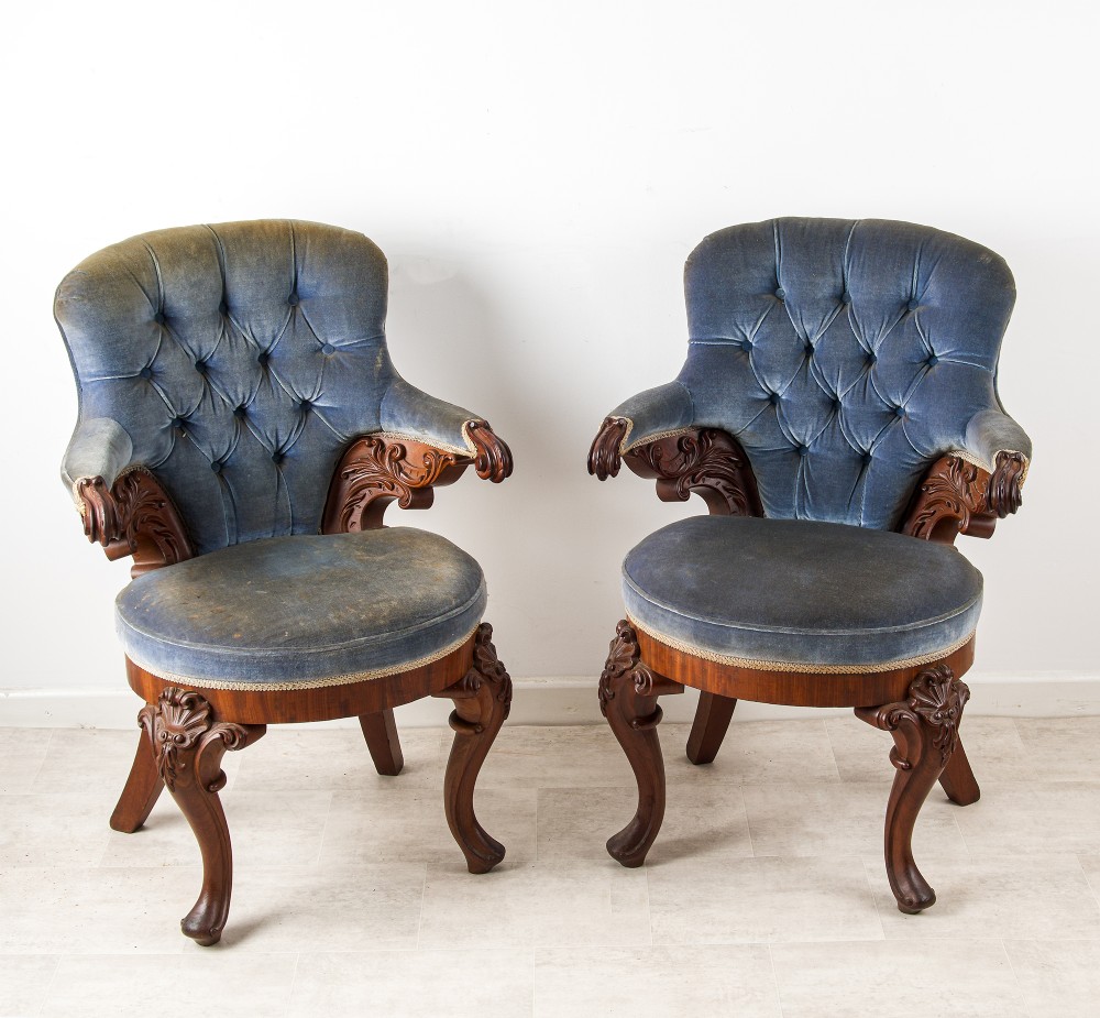 A pair of Victorian carved mahogany armchairs with button-backed blue velvet upholstery and detailed carved legs. View V