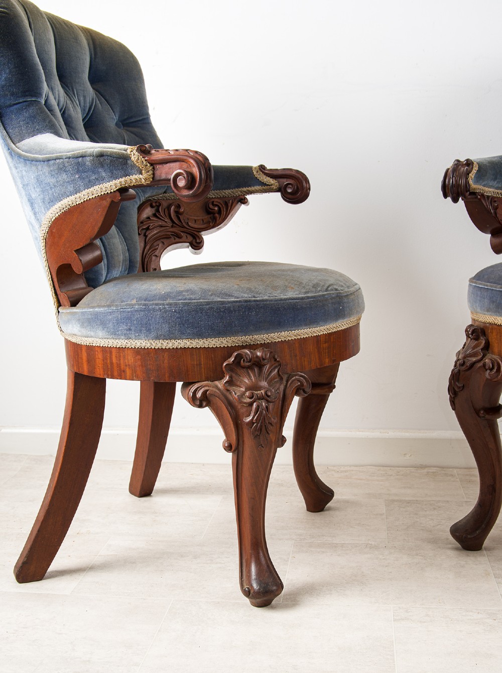 A pair of Victorian carved mahogany armchairs with button-backed blue velvet upholstery and detailed carved legs. View VI