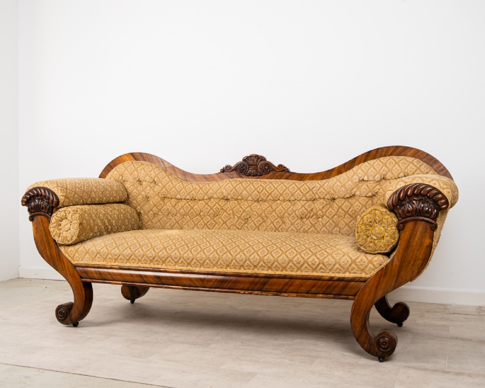 A Victorian rosewood settee featuring carved scroll ends, a central carved cresting, and patterned mustard yellow upholstery with bolster cushions. View II