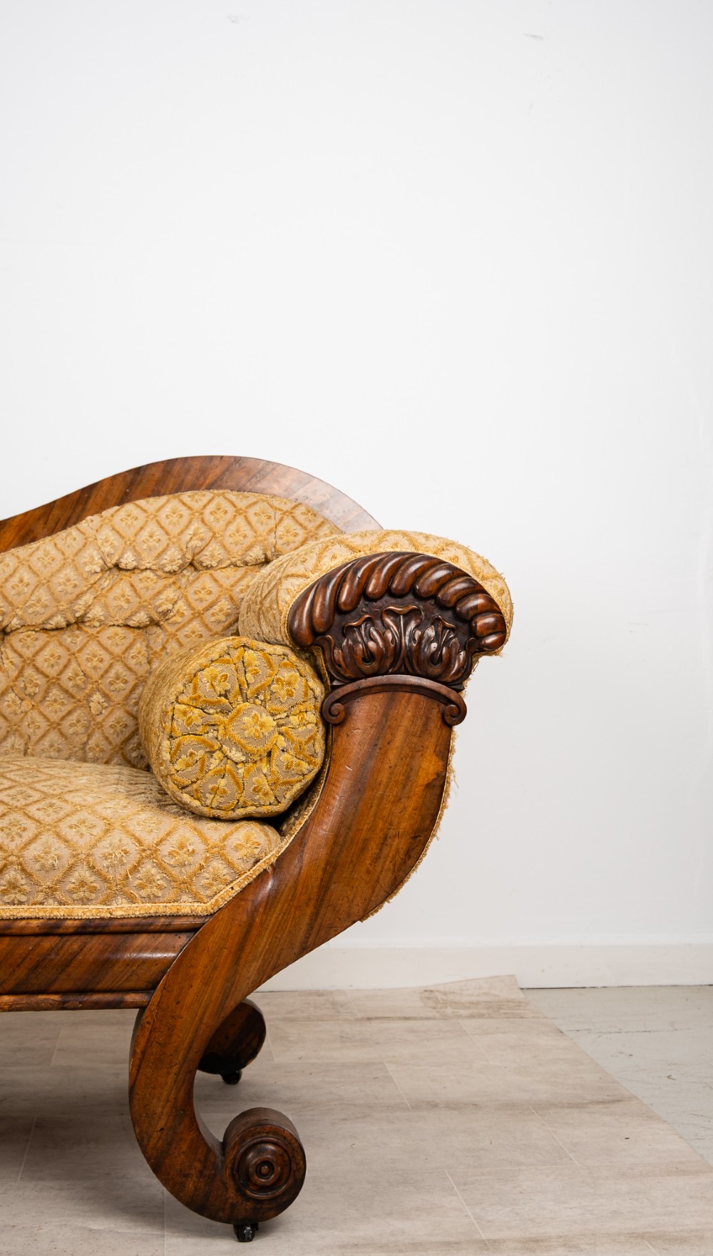 A Victorian rosewood settee featuring carved scroll ends, a central carved cresting, and patterned mustard yellow upholstery with bolster cushions. View IV