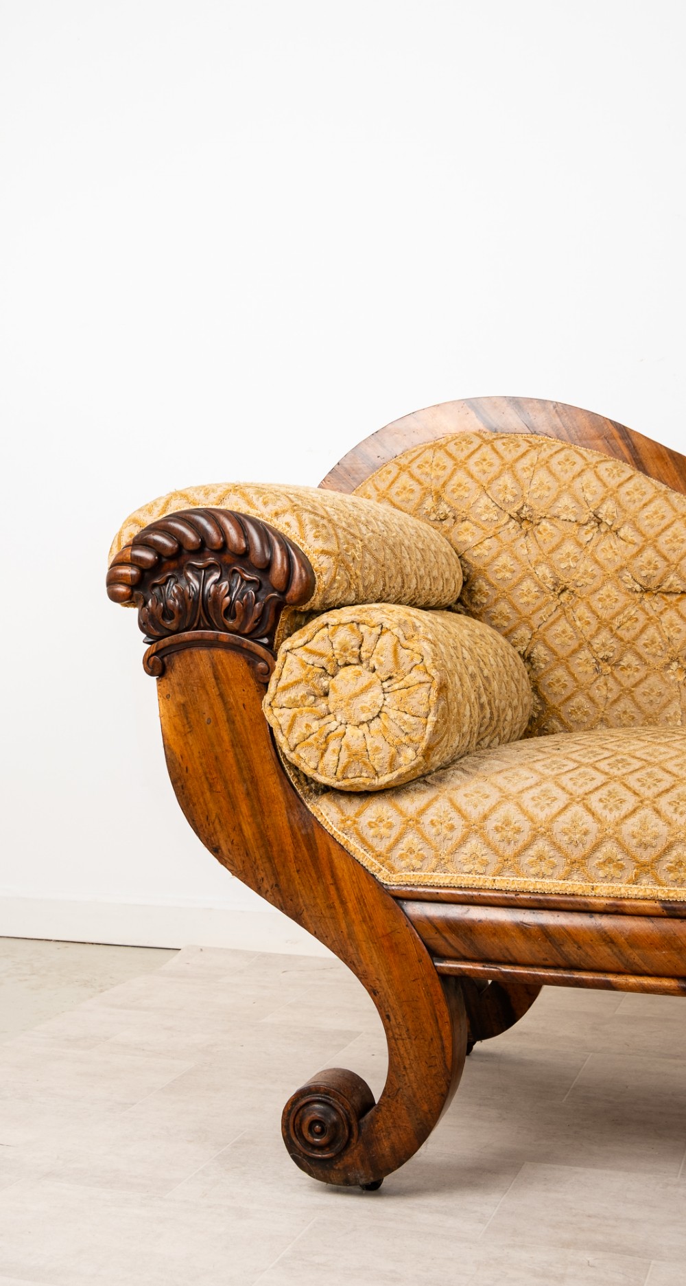 A Victorian rosewood settee featuring carved scroll ends, a central carved cresting, and patterned mustard yellow upholstery with bolster cushions. View V