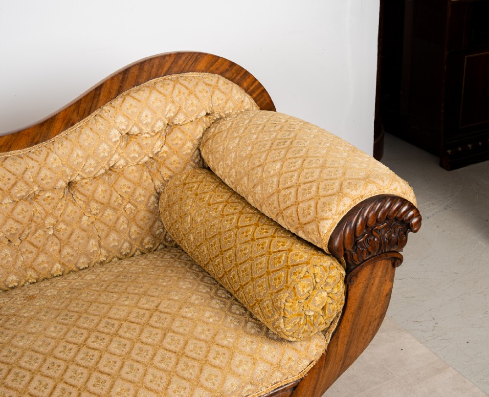 A Victorian rosewood settee featuring carved scroll ends, a central carved cresting, and patterned mustard yellow upholstery with bolster cushions. View VIII