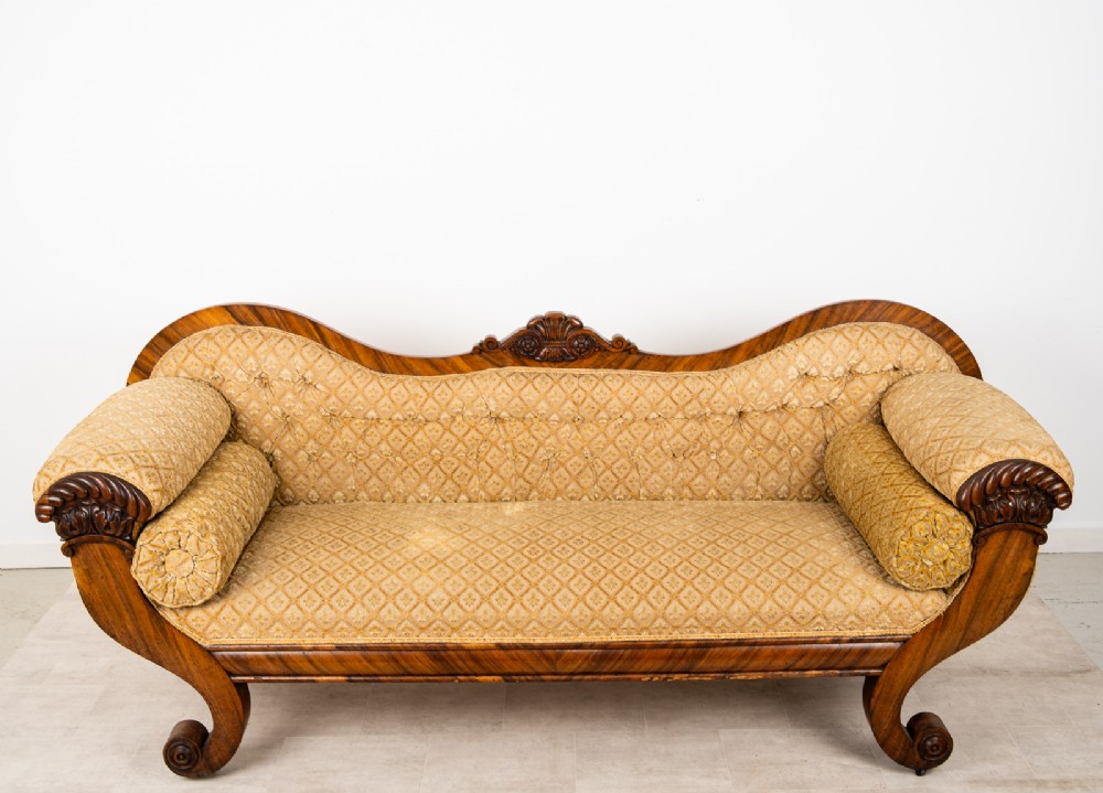 A Victorian rosewood settee featuring carved scroll ends, a central carved cresting, and patterned mustard yellow upholstery with bolster cushions. View IX