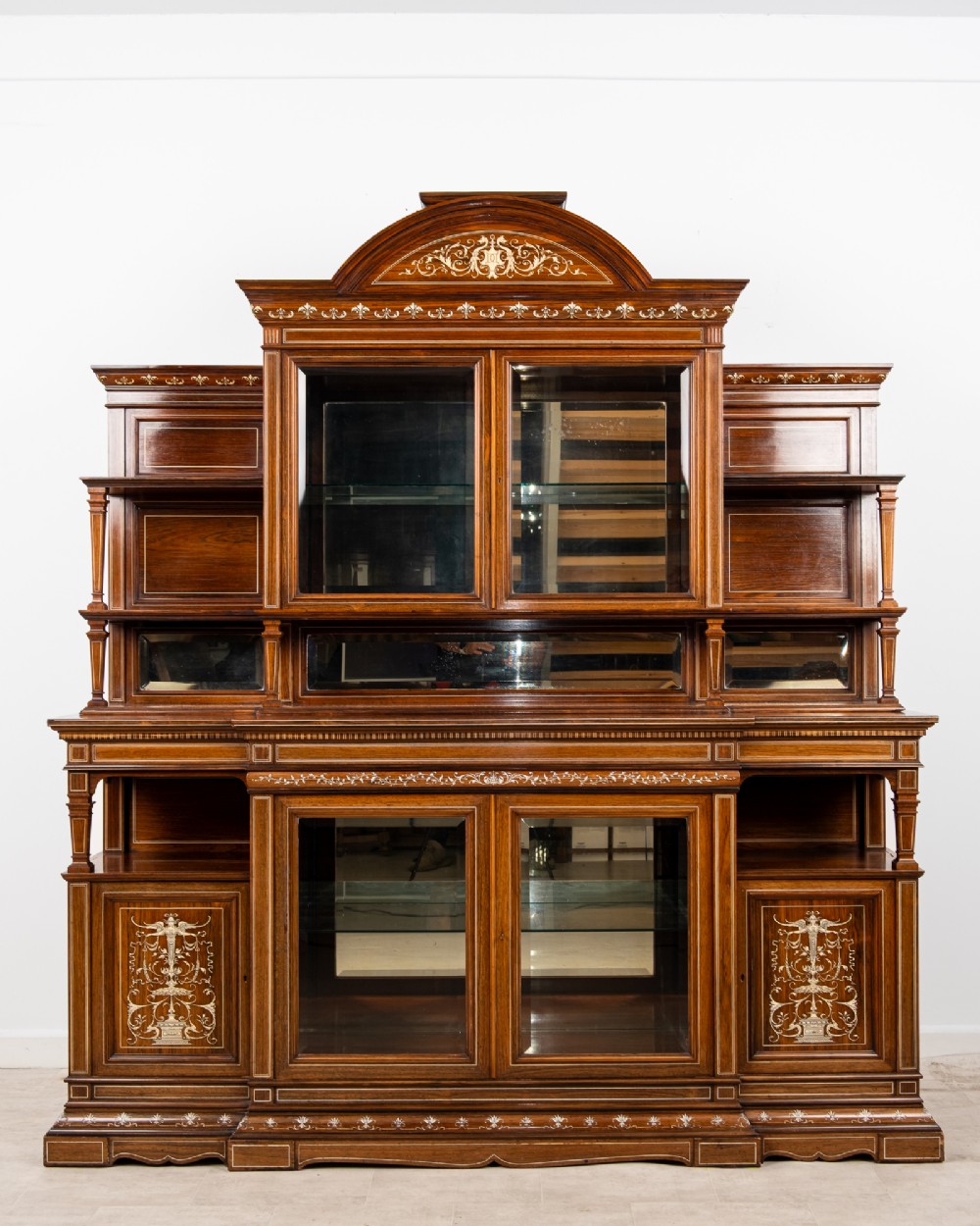 A monumental Victorian rosewood display cabinet featuring marquetry inlay, glazed doors, mirrored panels, and multi-tiered shelving.