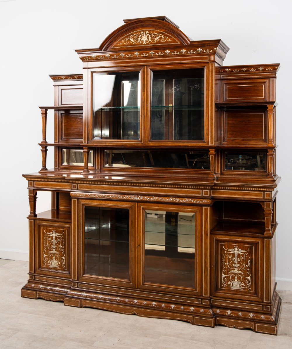 A monumental Victorian rosewood display cabinet featuring marquetry inlay, glazed doors, mirrored panels, and multi-tiered shelving. View IV