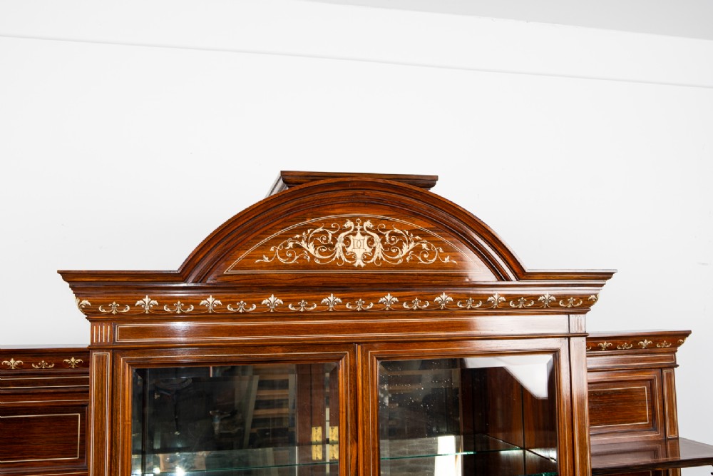 A monumental Victorian rosewood display cabinet featuring marquetry inlay, glazed doors, mirrored panels, and multi-tiered shelving. View VI