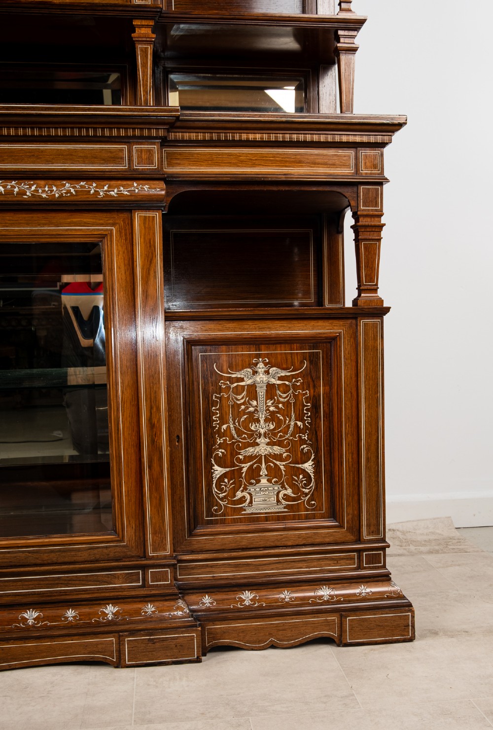 A monumental Victorian rosewood display cabinet featuring marquetry inlay, glazed doors, mirrored panels, and multi-tiered shelving. View VII
