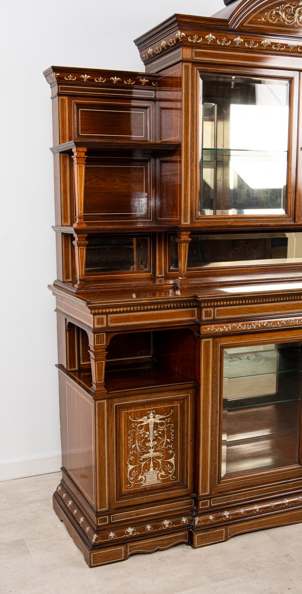 A monumental Victorian rosewood display cabinet featuring marquetry inlay, glazed doors, mirrored panels, and multi-tiered shelving. View X