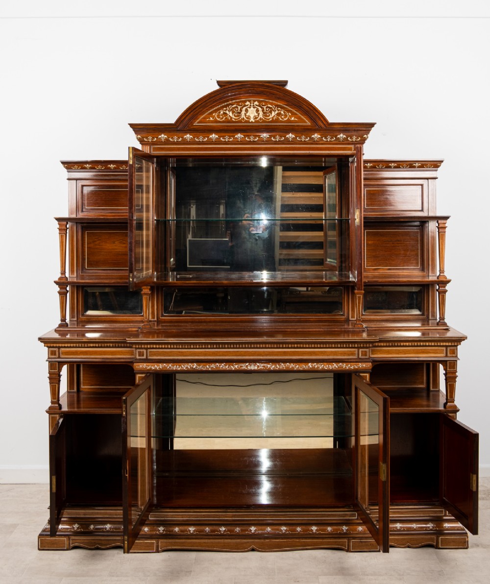 A monumental Victorian rosewood display cabinet featuring marquetry inlay, glazed doors, mirrored panels, and multi-tiered shelving. View XII