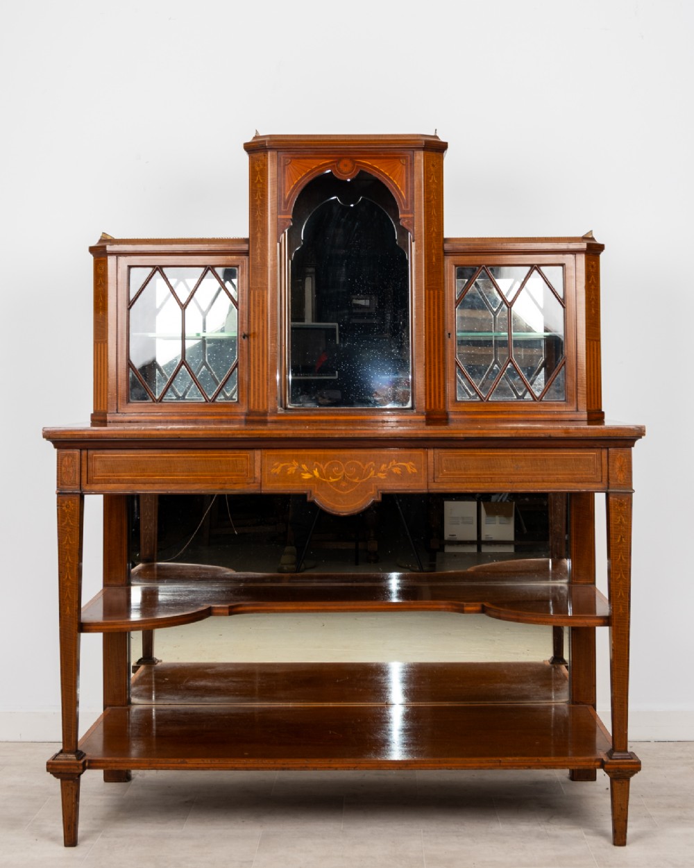 An Edwardian mahogany bonheur du jour writing desk featuring floral marquetry inlay, central mirrored recess, glazed side cabinets, and open lower shelves. View II