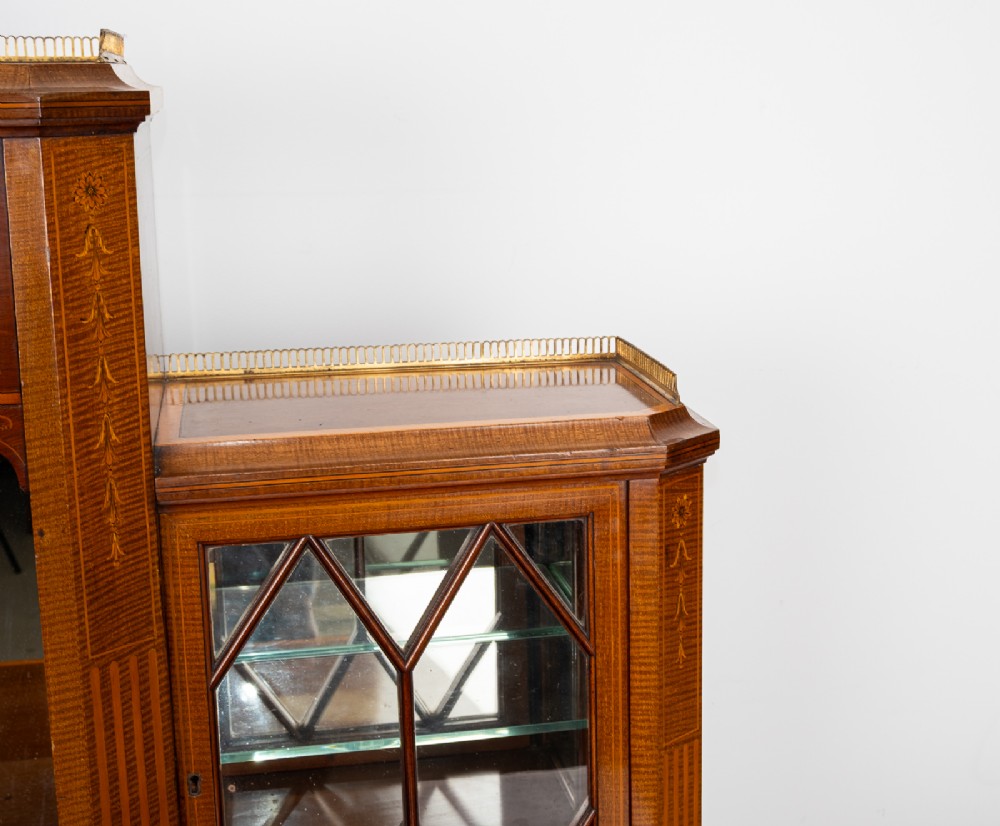 An Edwardian mahogany bonheur du jour writing desk featuring floral marquetry inlay, central mirrored recess, glazed side cabinets, and open lower shelves. View V