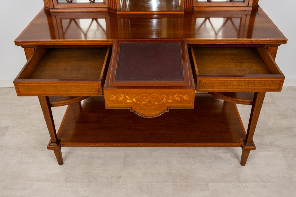 An Edwardian mahogany bonheur du jour writing desk featuring floral marquetry inlay, central mirrored recess, glazed side cabinets, and open lower shelves. View VII