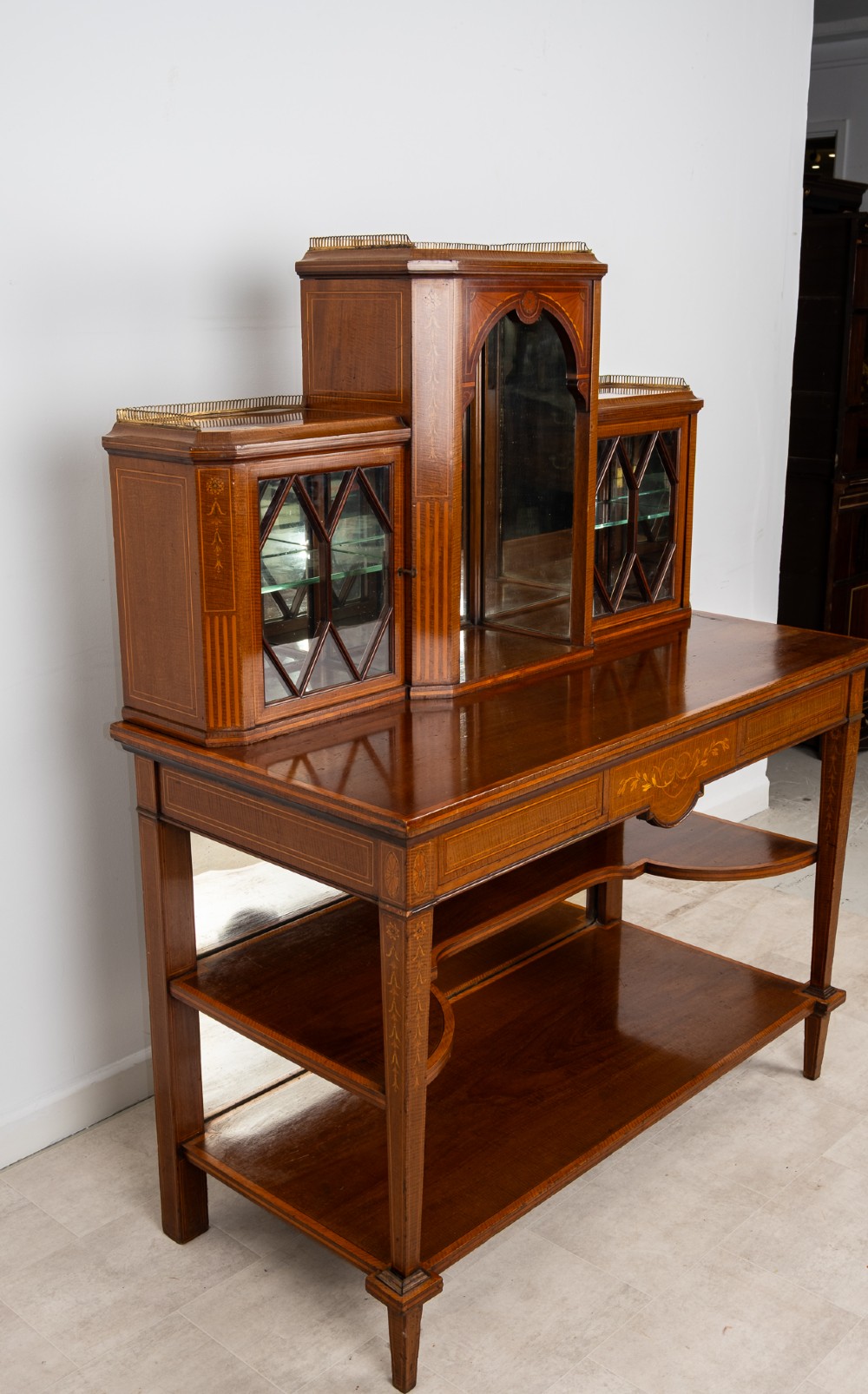 An Edwardian mahogany bonheur du jour writing desk featuring floral marquetry inlay, central mirrored recess, glazed side cabinets, and open lower shelves. View IX